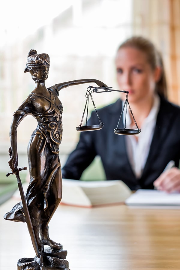 Lawyer sitting at desk with lady justice statue