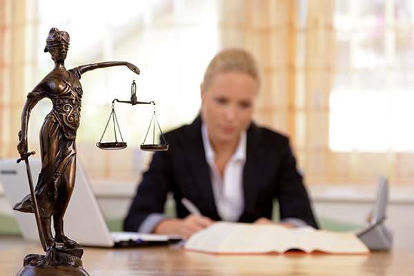 Lawyer sitting at desk with lady justice statue